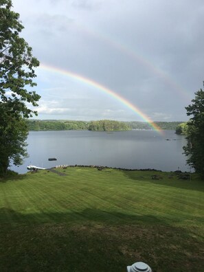 Une zone herbeuse offrant une vue sur un lac et un arc-en-ciel.