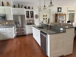 A kitchen with white cabinetry, granite countertops, stainless steel appliances, and a dishwasher.