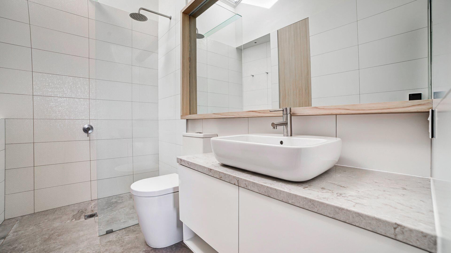 Une salle de bain moderne avec un lavabo blanc, des toilettes et un espace douche.