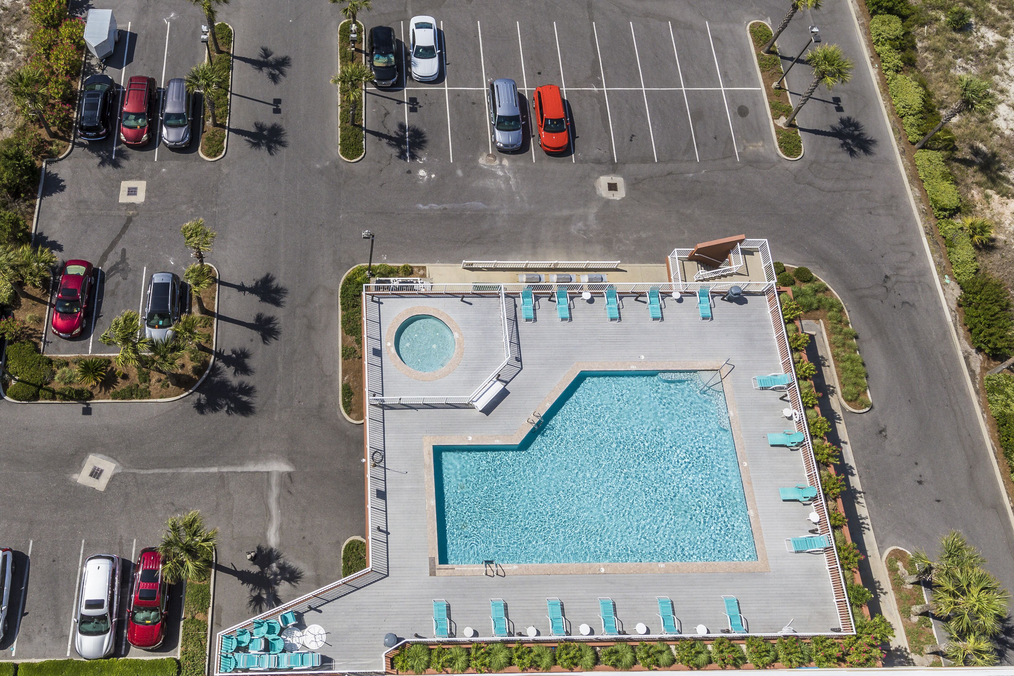 Vista aérea de un hotel con piscina, estacionamiento y zona de lounge.
