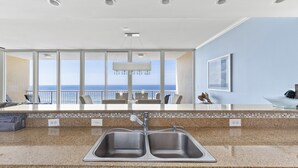 Una cocina moderna con un lavamanos doble, encimera de granito y vista al océano.