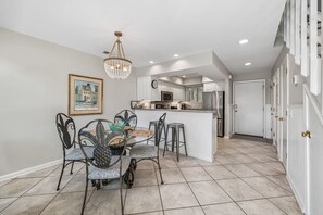 A kitchen with white cabinets, a dining area with a chandelier, and a framed picture on the wall. - Mariners Walk 10E in Wild Dunes- Ocean front 3 bedroom villa Isle of Palms with community pool. (Isle of Palms)