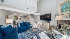 Ein großzügiges Wohnzimmer mit einem blauen Sofa, einem Couchtisch und einem Fernseher.