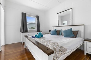 Ein Schlafzimmer mit einem großen Bett, einem Nachttisch, einem Fenster mit Vorhängen und einem Spiegel an der Wand.
