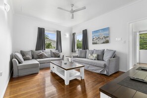 Ein modernes Wohnzimmer mit zwei grauen Sofas, einem Holztisch und einem Deckenventilator.