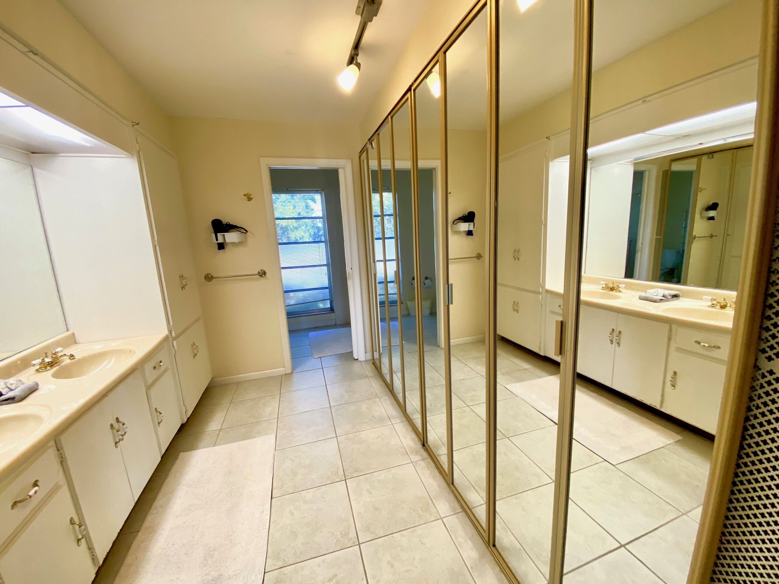 A hotel bathroom with a large mirror, a sink, and a shower area.