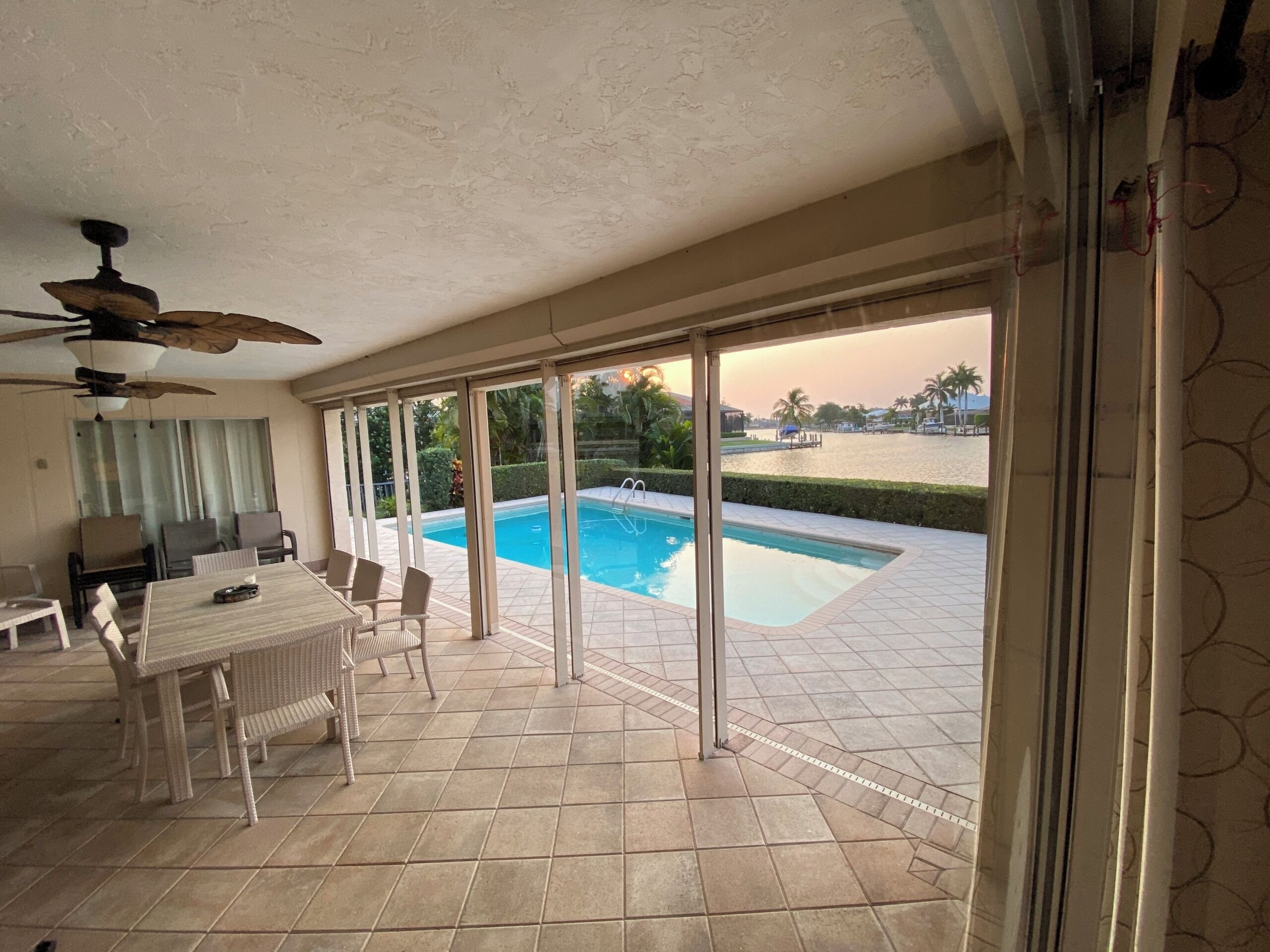 A spacious indoor area with a pool, sliding glass doors, a ceiling fan, and a dining table with chairs.