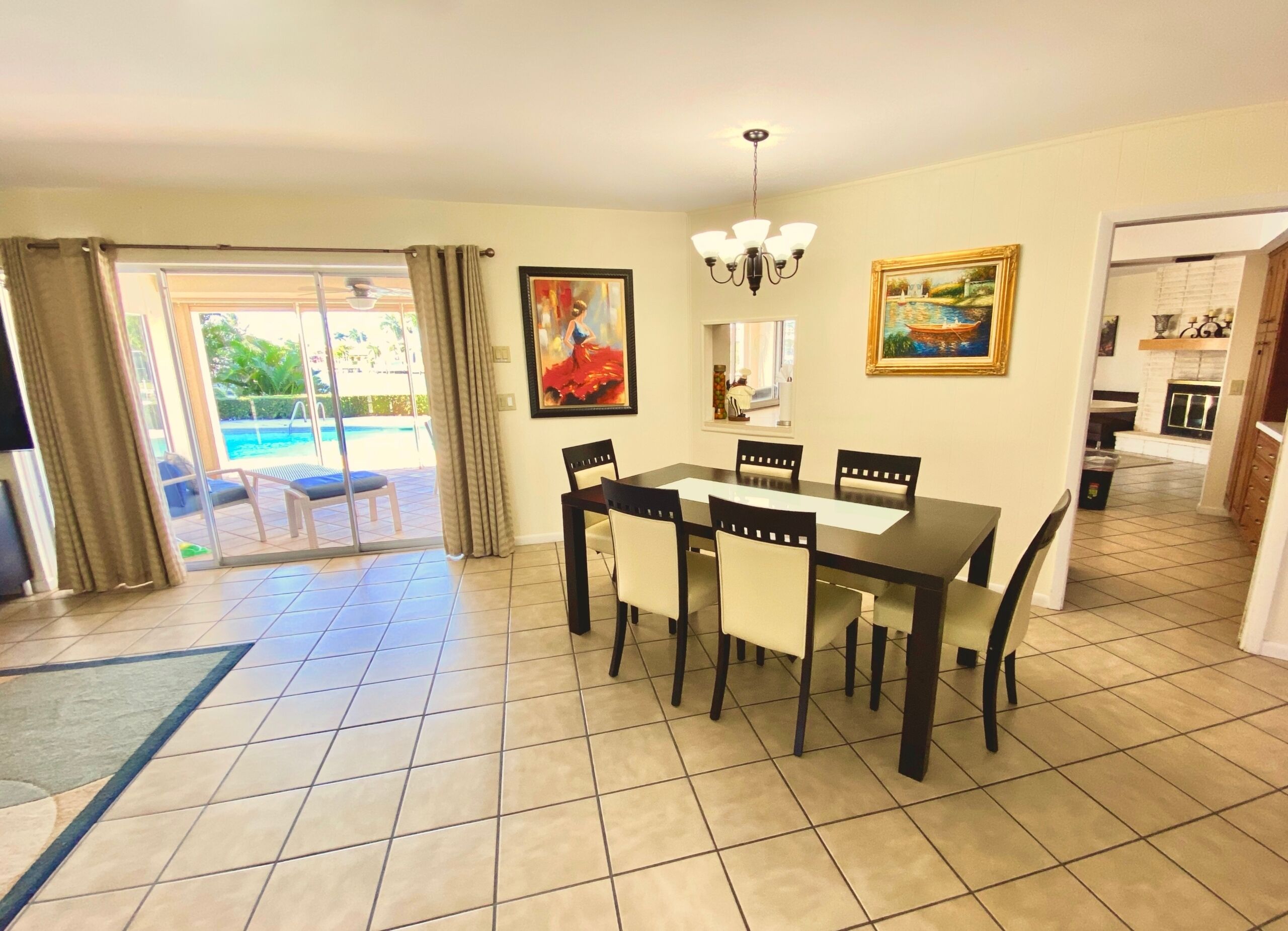 A dining area with a table and chairs, a chandelier, and a painting on the wall.