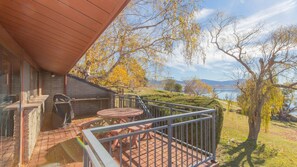 Un balcone con tavolo e sedie, vista su un lago e alberi.