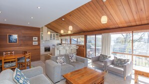 A modern interior with a wooden ceiling, a kitchen area, and a seating area with sofas and a coffee table.