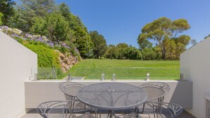 A patio with a round table and chairs, overlooking a grassy area with trees and a clear sky. - Horizons - 505/10 Kosciuszko (Jindabyne)