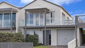 A modern two-story house with a balcony, large windows, and a garage.