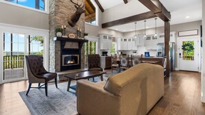 A spacious living room with a fireplace, a stone accent wall, and a large window overlooking a deck.