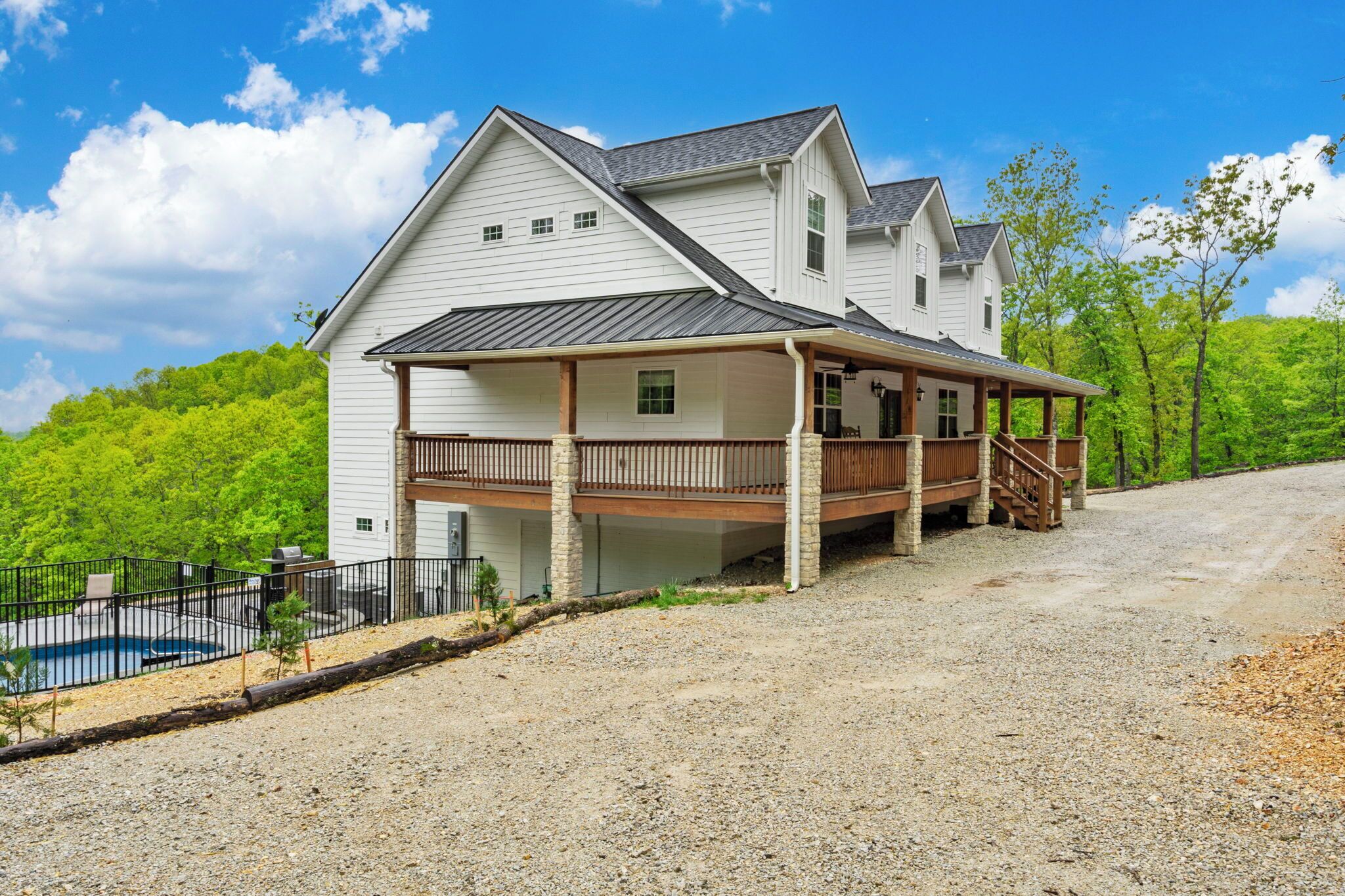 A two-story house with a covered porch and a swimming pool.