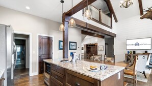 A spacious kitchen with a large island, wooden cabinets, and a chandelier.