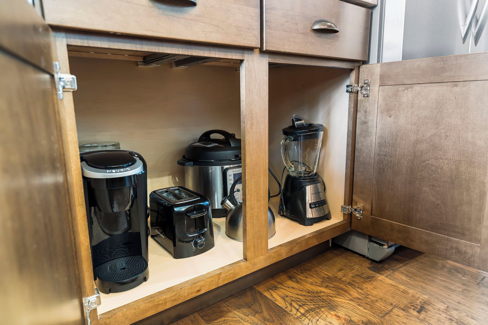 Une cuisine équipée d’un meuble encastré contenant une machine à café, un mixeur et un appareil de cuisson à basse température.