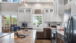 A modern kitchen with white cabinetry, a granite countertop, a stainless steel refrigerator, and a window providing natural light.