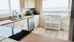 Een keuken met uitzicht op zee, een magnetron en een spoelbak.