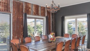 A dining room with a wooden table and chairs, large windows with views of a landscape, and a chandelier. - Oak & Barrell - 7 Twynam Street (Jindabyne)