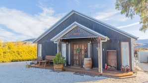 A rustic wooden building with a porch, wooden barrels, and outdoor seating. - Oak & Barrell - 7 Twynam Street (Jindabyne)