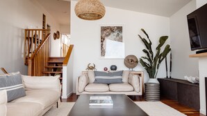 A modern living room with a sofa, coffee table, and a staircase. - Escape 2 Brophy - Southern Ocean Views (Port Fairy)
