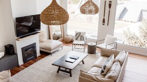 A modern living room with a TV, sofas, a coffee table, and wicker pendant lights. - Escape 2 Brophy - Southern Ocean Views (Port Fairy)
