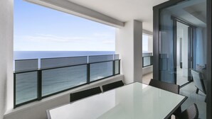 A balcony with a glass railing overlooking the ocean.