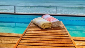 A wooden deck with a pool and towels, overlooking a turquoise sea under a partly cloudy sky. - A Surfer's Home Away From Home! Soft round the edges, cozy and beachy (Oistins)