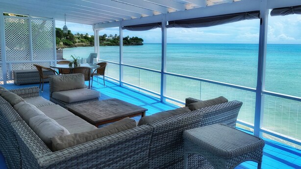 A covered outdoor seating area with wicker furniture and a view of the ocean. - A Surfer's Home Away From Home! Soft round the edges, cozy and beachy (Oistins)