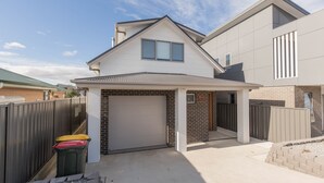 A modern two-story house with a garage, a covered patio, and a brick exterior. - 43A Twynam Street - Spacious four bedroom home in central Jindabyne location (Jindabyne)