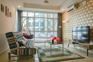 Relax in this stylish living room with a city view, featuring a striped sofa, hanging chair, and flat-screen TV.