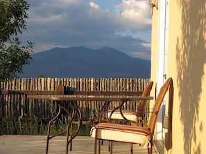 Um deck de madeira com mesa e cadeiras, com vista para uma cordilheira.