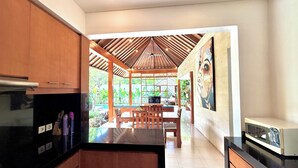 Une cuisine moderne avec des meubles en bois, un plan de travail noir et un coin repas comprenant une table et des chaises en bois.
