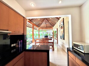 Una cocina moderna con armarios de madera, encimera negra y comedor con mesa y sillas de madera.