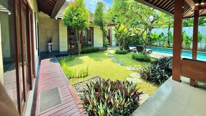 Un espace extérieur abrité, doté d’une piscine, entouré de verdure et bordé d’un bâtiment aux grandes fenêtres.