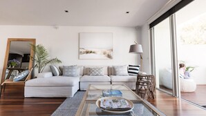 A modern living room with a sofa, a coffee table, and a large window. - Spinnakers Waterfront (Port Fairy)