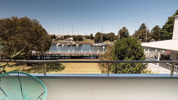 A balcony with a view of a marina, docked boats, and a clear sky.
