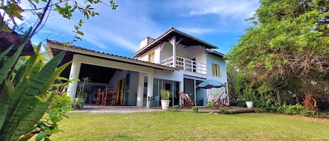 A two-story house with a balcony, a covered patio, and a well-maintained lawn.