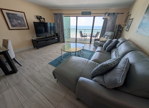 Sala de estar con sofá, televisión y balcón con vistas.
