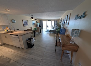 Una cocina moderna con comedor, ventilador de techo y vista al salón.