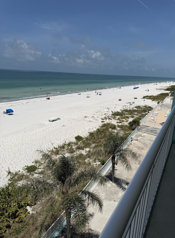 Una playa con sombrillas, cielo despejado y vista al océano.