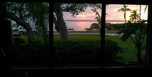 Ein See mit Sonnenuntergang, Bäumen und einem parkenden Auto.
