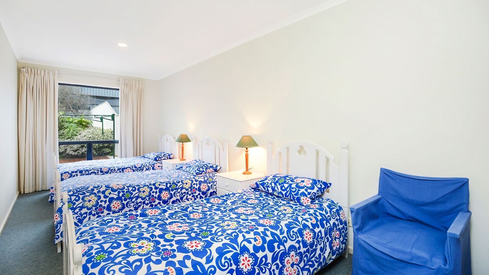 A hotel room with two beds, a chair, and a window with curtains.