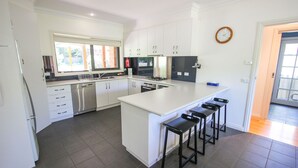 Una cocina moderna con armarios blancos, un refrigerador de acero inoxidable, un horno integrado y una isla grande con taburetes de bar.