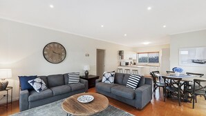 Ein modernes Wohnzimmer mit zwei grauen Sofas, einem Holztisch und einer großen Wanduhr.