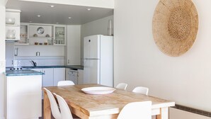 Una cucina moderna con mobili bianchi, un piano di lavoro blu e un tavolo da pranzo in legno con sedie bianche.