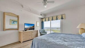 Un dormitorio con una cama grande, televisor, una silla y ventana con vistas.