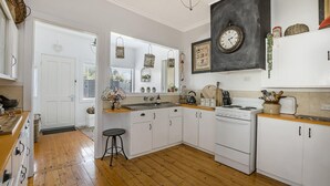 Een keuken met witte kastjes, een fornuis, een spoelbak en een houten aanrecht.