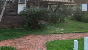 Un patio con un sendero de ladrillo, palmeras y un edificio con techo de tejas.