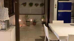 Una cocina moderna con un refrigerador azul, armarios blancos y un comedor con una mesa y sillas blancas.